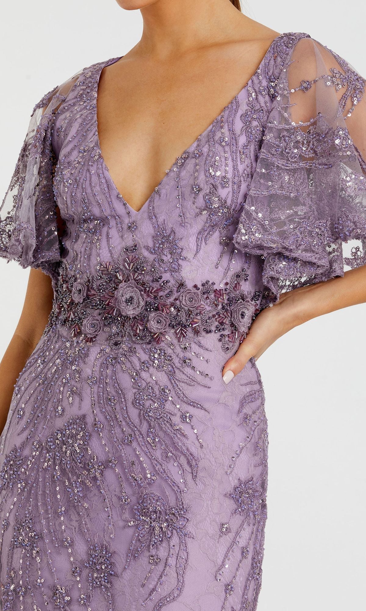 A woman wearing the Long Formal Dress 67493 by Mac Duggal, featuring a lavender hue, empire waist, beaded floral embroidery, flutter sleeves, and a deep V-neckline.